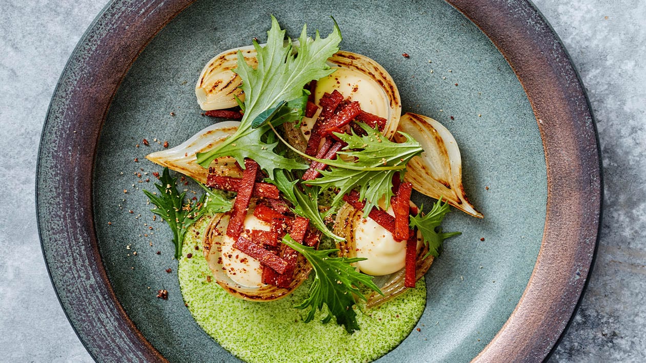 Geroosterde ui met gerookte kaas crème, vegetarische spekjes en mosterdsla Geroosterde ui met gerookte kaas crème, vegetarische spekjes en mosterdsla